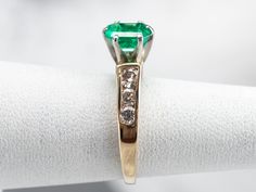 This emerald and diamond ring is classic, yet dazzling! The emerald is hypnotic and dreamy, with an iconic green hue that can't help but draw your eye. Bright and sparkling diamonds cascade down the shoulders of the ring, creating a gorgeous play of light. Metal: Platinum (Head), 14K Yellow Gold Gem: Emerald .94 Carats Gem Measurements: 4.6 x 6.4 mm, Emerald Cut Accents: 6 Diamonds totaling .42 Carats, SI in Clarity, H in Color Ring Size: 4.25 Marks: "88 14K" Stamped on the inside band Green Princess Cut Diamond Ring In Fine Jewelry Style, Fine Jewelry Green Princess Cut Diamond Ring, Green Princess Cut Diamond Ring Fine Jewelry, Green Princess Cut Diamond Ring, Emerald Cut Green Diamond Ring With Prong Setting, Green Emerald Ring With Diamond Accents, Green Diamond Ring With Vvs Clarity For May Birthstone, Emerald Cut Green Diamond Ring With Diamond Accents, Green Diamond Ring With Prong Setting