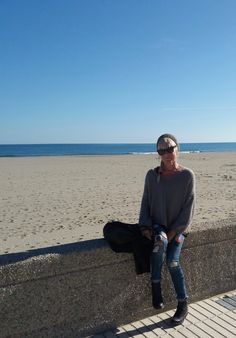 a person sitting on a wall near the beach