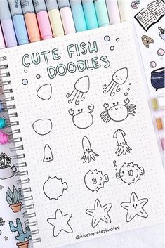 an open notebook with doodles on it next to crayon markers and pens