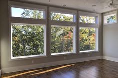 an empty room with large windows and hard wood flooring