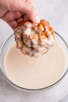 a person dipping some kind of pastry into a bowl of milkshake sauce with a bite taken out of it