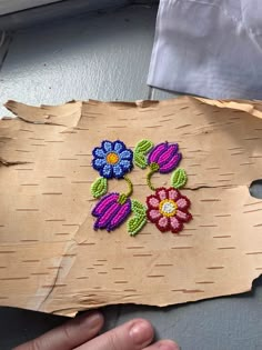 a piece of paper with flowers on it and a person's hand next to it