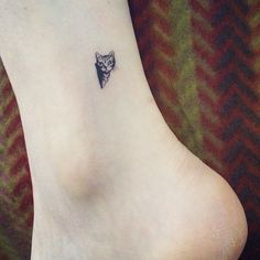 a small tattoo on the foot of a person with a cat's head in it