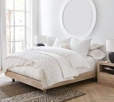 a bedroom with a bed, nightstands and large round mirror on the wall above it