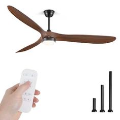 a person holding a remote control in front of a ceiling fan with three blades attached to it