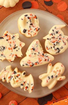 halloween cookies with white frosting and sprinkles on a plate