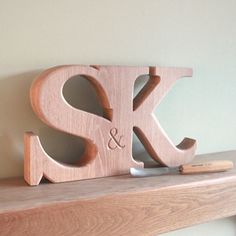 a wooden letter shaped like the letters s and k on a shelf next to a pen