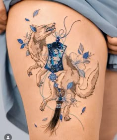 a woman's thigh with tattoos on it and a tattoo design in the shape of a wolf