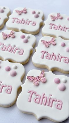 decorated cookies with pink and white icing are arranged on a tablecloth that says tahitira