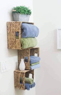 towels are stacked in baskets on the wall next to a vase with flowers and a potted plant