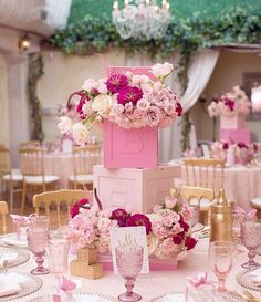 the table is set up with pink and white flowers in boxes on top of each other