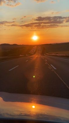 the sun is setting on an empty highway