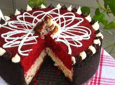 a red velvet cake with white icing on a checkered tablecloth and green leaves