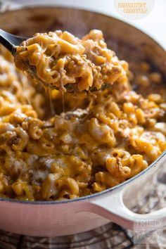 a spoon full of macaroni and cheese being lifted from a pot