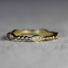 a yellow gold wedding band with three diamonds on the top and bottom, sitting on a white surface