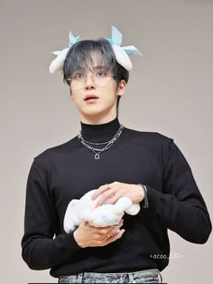 a young man with horns on his head is holding a stuffed animal in his hands