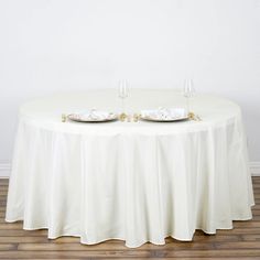 two empty wine glasses sitting on top of a white table cloth covered round dining table