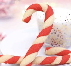 two candy canes sitting on top of a white plate next to a cup and saucer