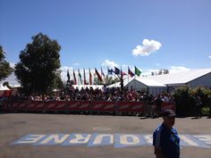 a man standing in front of a fence with flags on it and people watching from the sidelines