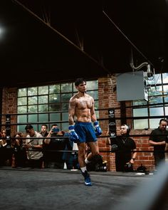 a shirtless man is walking in the middle of a boxing ring with his hands on his hips