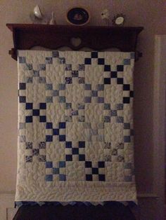 a white and blue quilt hanging on a wall