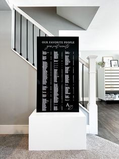 a black and white sign sitting in the middle of a room next to a stair case