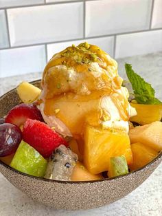 a bowl filled with fruit and ice cream on top of a marble counter next to a white tile wall