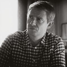 black and white photograph of a man sitting in front of a window looking at something