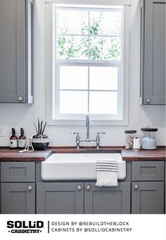 a white sink sitting under a window next to a wooden counter top in a kitchen