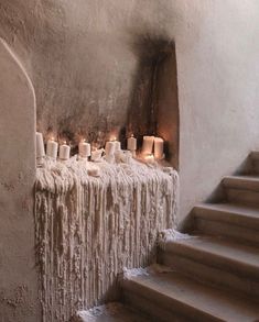 candles are lined up on the wall next to some concrete steps with white fur hanging from them