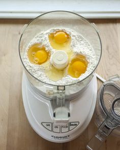 three eggs in a food processor on a wooden table