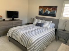 a bedroom with a bed, dresser and television