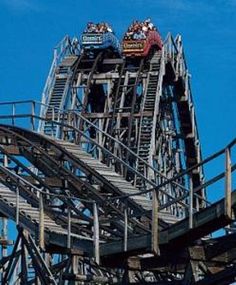 people ride the roller coaster at an amusement park on a clear day with blue skies in the background