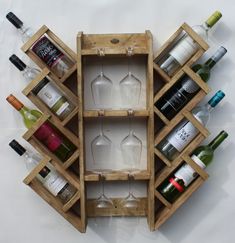 a wooden wine rack filled with bottles and glasses next to each other on a white surface