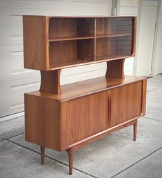 a wooden cabinet sitting on top of a cement floor next to a white garage door