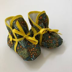 a pair of baby shoes with yellow ribbon tied around the top and bottom, sitting on a white surface