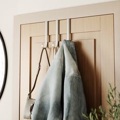 an old pair of jeans hanging on a coat rack next to a potted plant