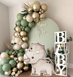 a baby shower is decorated with gold and green balloons, greenery, and an elephant cutout