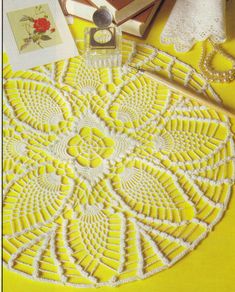 a yellow doily sitting on top of a table next to a bottle of perfume