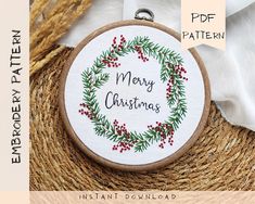 a christmas wreath with the words merry christmas printed on it in red and green embroidery