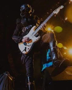 a man with a guitar in his hand and some lights on the ground behind him