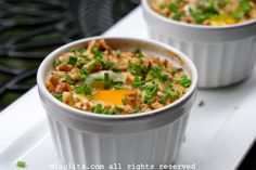 two white bowls filled with food sitting on top of a table next to each other