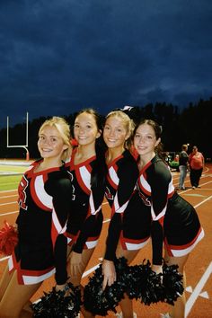 the cheerleaders are posing for a photo on the field at night with their pom poms