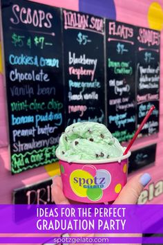 a person holding up a cup of ice cream in front of a chalkboard menu