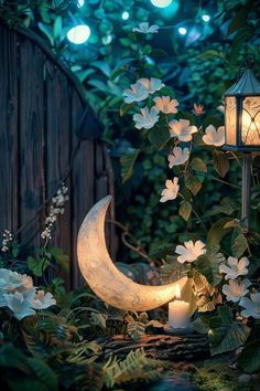 the moon is lit up next to some flowers and a lantern in front of it