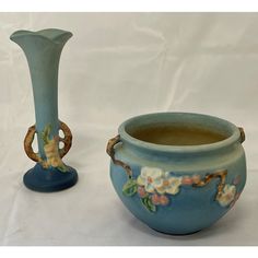 two vases with flowers painted on them sitting next to each other in front of a white background