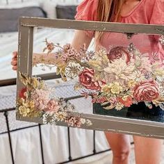 a woman is holding up a mirror with flowers on it and she has her hand in the frame