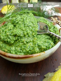 a bowl filled with green sauce on top of a wooden table