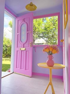 a vase with flowers on a table in front of a pink door