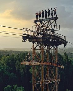 several people standing on top of a metal structure in the middle of trees and hills